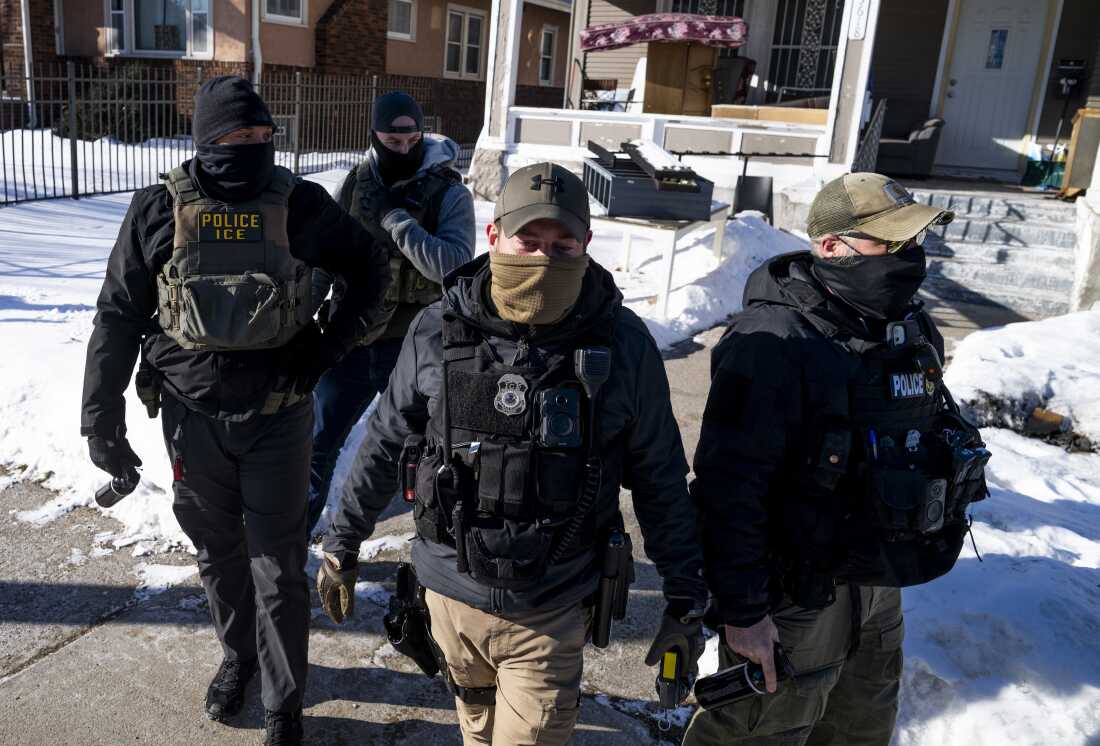 Masked ICE agents leave a residence after knocking on the door in Minneapolis on Wednesday.