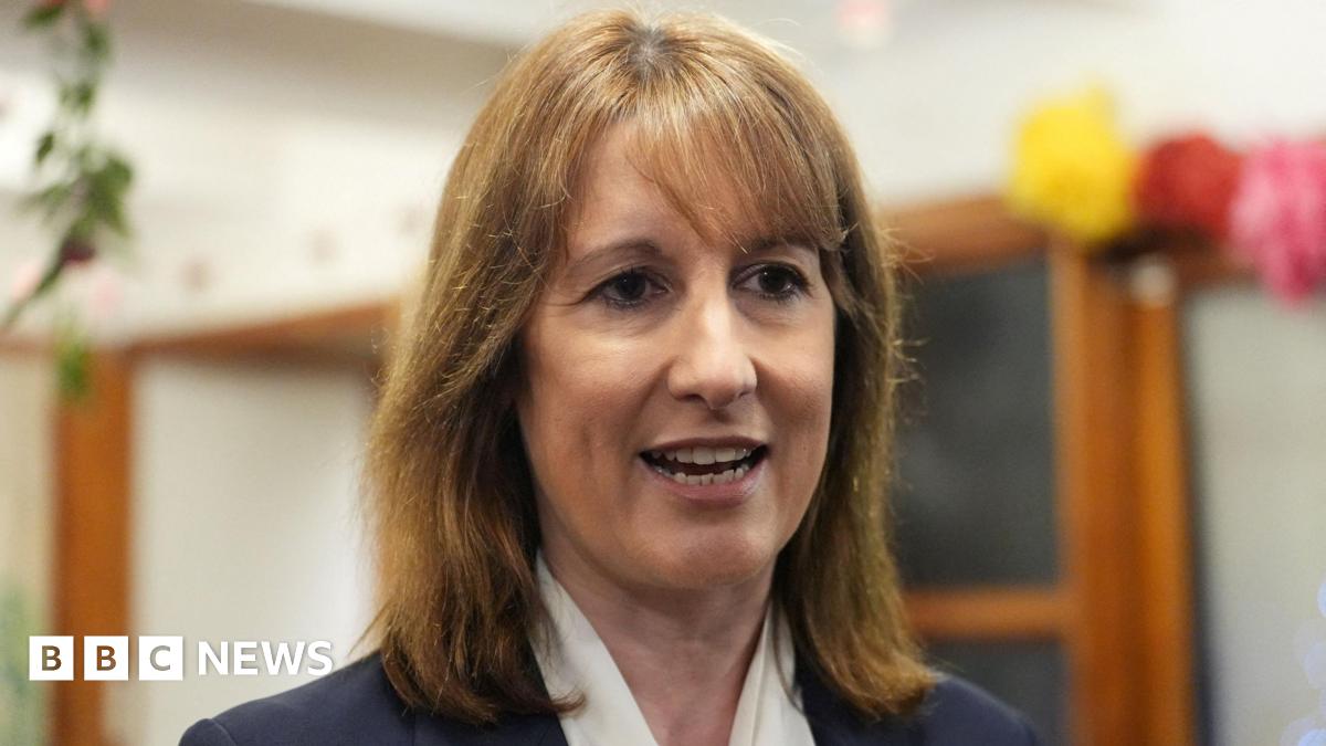 Prime Minister Mark Carney, wearing a black suit jacket, and a white button-up shirt leans his chin on his hands. He has short grey and black hair and is looking away from the camera.