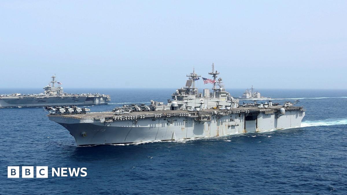 Aircraft carrier USS Abraham Lincoln is seen in the open ocean, with a US flag clearly visible.