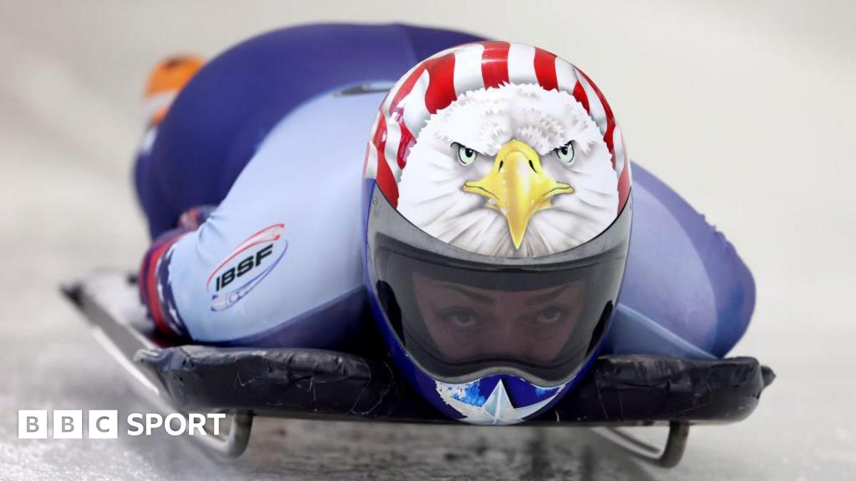 Katie Uhlaender competing the women’s skeleton World Championships in 2025. She is wearing a crash helmet which is painted with an image of an American eagle and the stars and stripes of the USA flag. Her eyes can be seen through a clear visor.