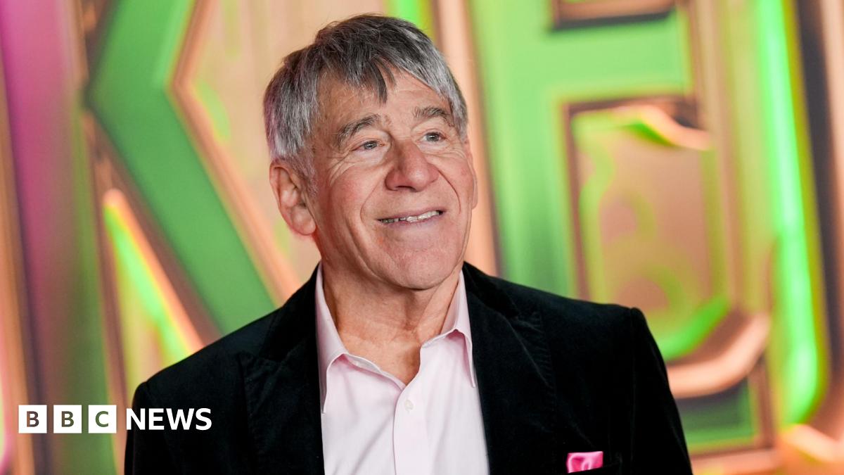 Stephen Schwartz at the "Wicked: For Good" New York Premiere held at Lincoln Center for the Performing Arts. He wears an open-neck pink shirt and black blazer.