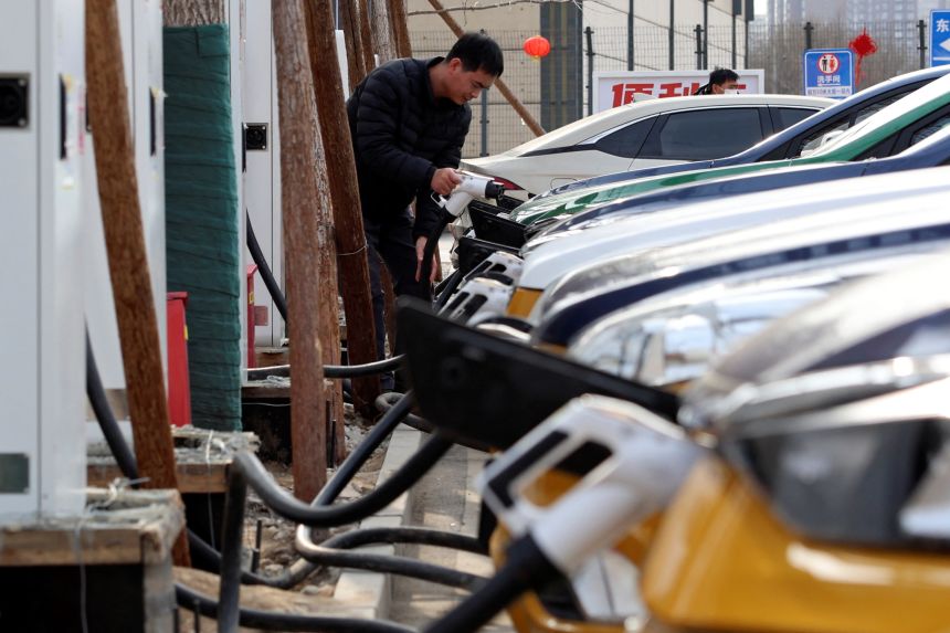 A man holds a plug to charge a car at an electric vehicle charging station in Beijing, China February 2, 2024. REUTERS/Florence Lo