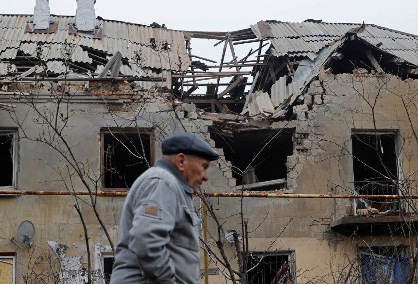 A man walks past a damaged apartment building in Donetsk, a Russian-controlled city of Ukraine, on November 30, 2025.
