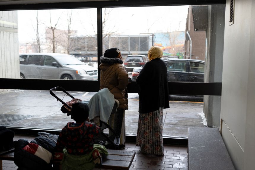 Somali residents look out of the lobby of the Riverside Plaza, an apartment complex popular among Somali-Americans, in Minneapolis amid reports of a planned federal operation targeting Somali immigrants on December 2, 2025.