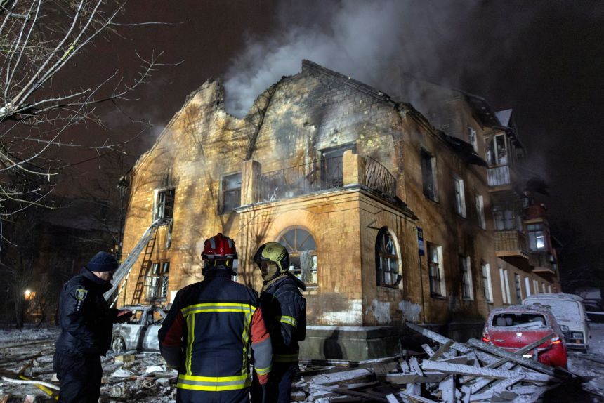 Firefighters stand in front of a residential building that was hit during a night of Russian drone and missile attacks in the Ukrainian capital.
