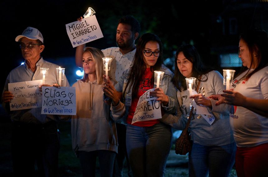 Family members hold candles and posters during a vigil outside the El Rodeo jail in Guatire, Venezuela, on Saturday.