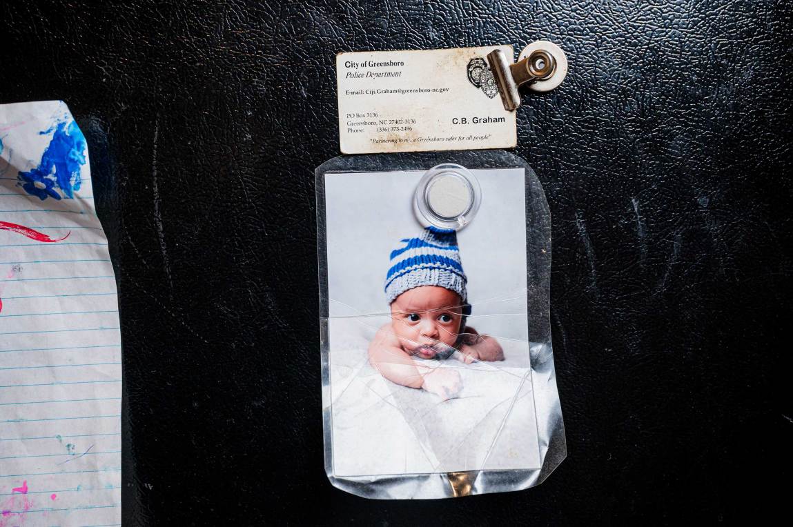 Graham’s business card from the Greensboro Police Department hangs on the fridge in Shawn Scott’s home above a baby picture of their son, SJ. Graham used to leave love notes on the fridge for Scott before she left for work. 