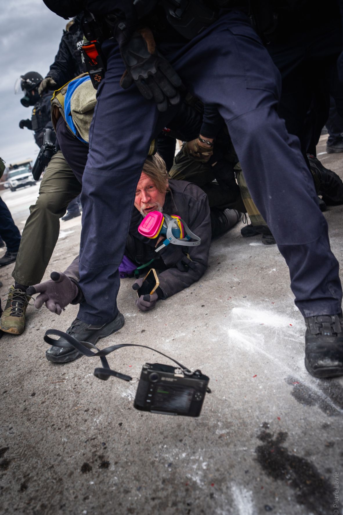 John Abernathy throws his camera toward fellow photographer Pierre Lavie as he is tackled by federal agents in Minneapolis on January 15. Abernathy was photographing protests in the city and said agents set tear gas in front of him and sprayed pepper spray into his face. The Department of Homeland Security said Abernathy was arrested for obstructing pedestrian and vehicle traffic on federal property.