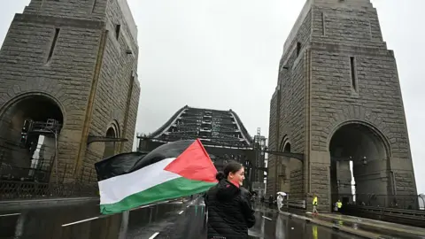Getty Images A protester with the Palestinian flag marches on the Sydney Harbour Bridge