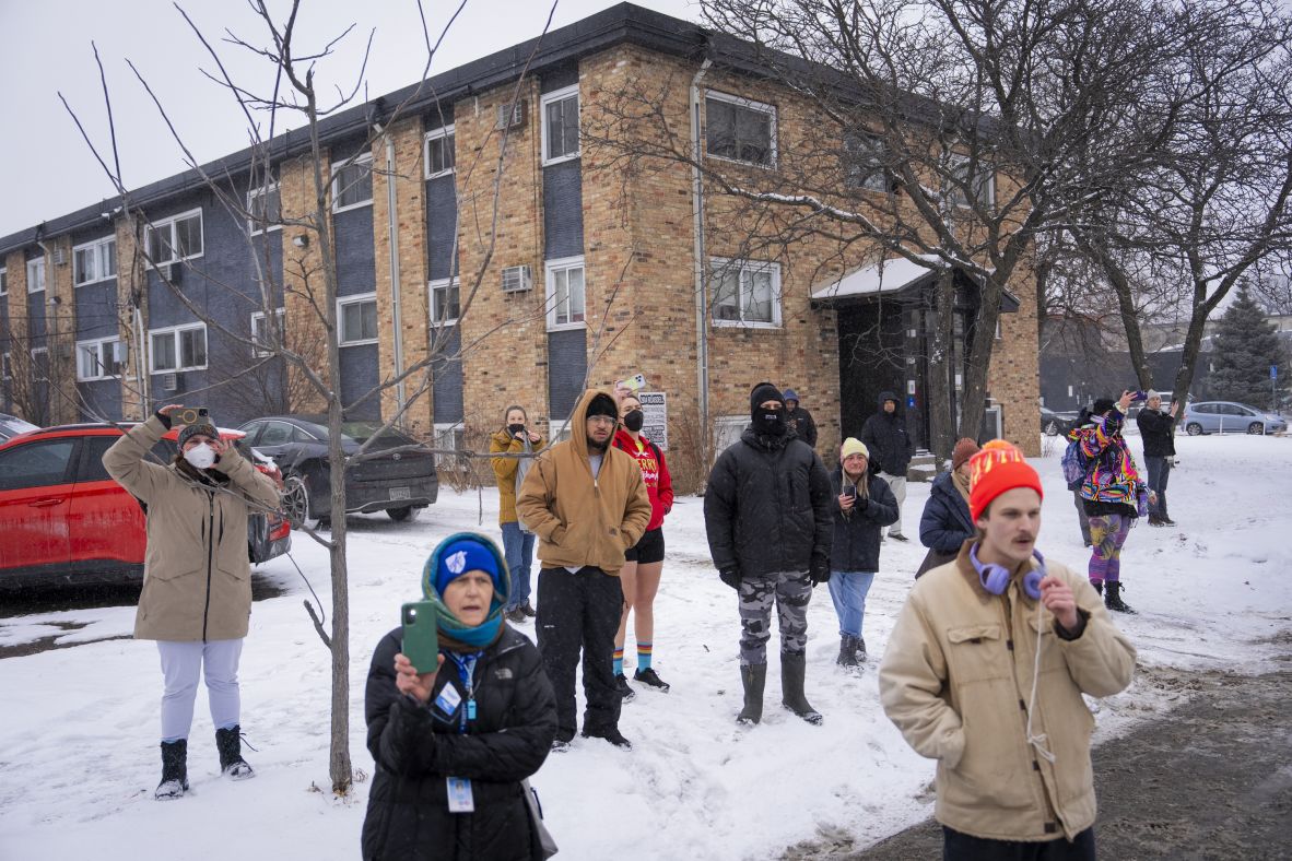 Community members look on as federal agents detain protesters at the scene of a car crash that involved a Border Patrol vehicle in Minneapolis on January 21.