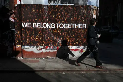 EPA A man walks past a poster containing the phrase "we belong together"