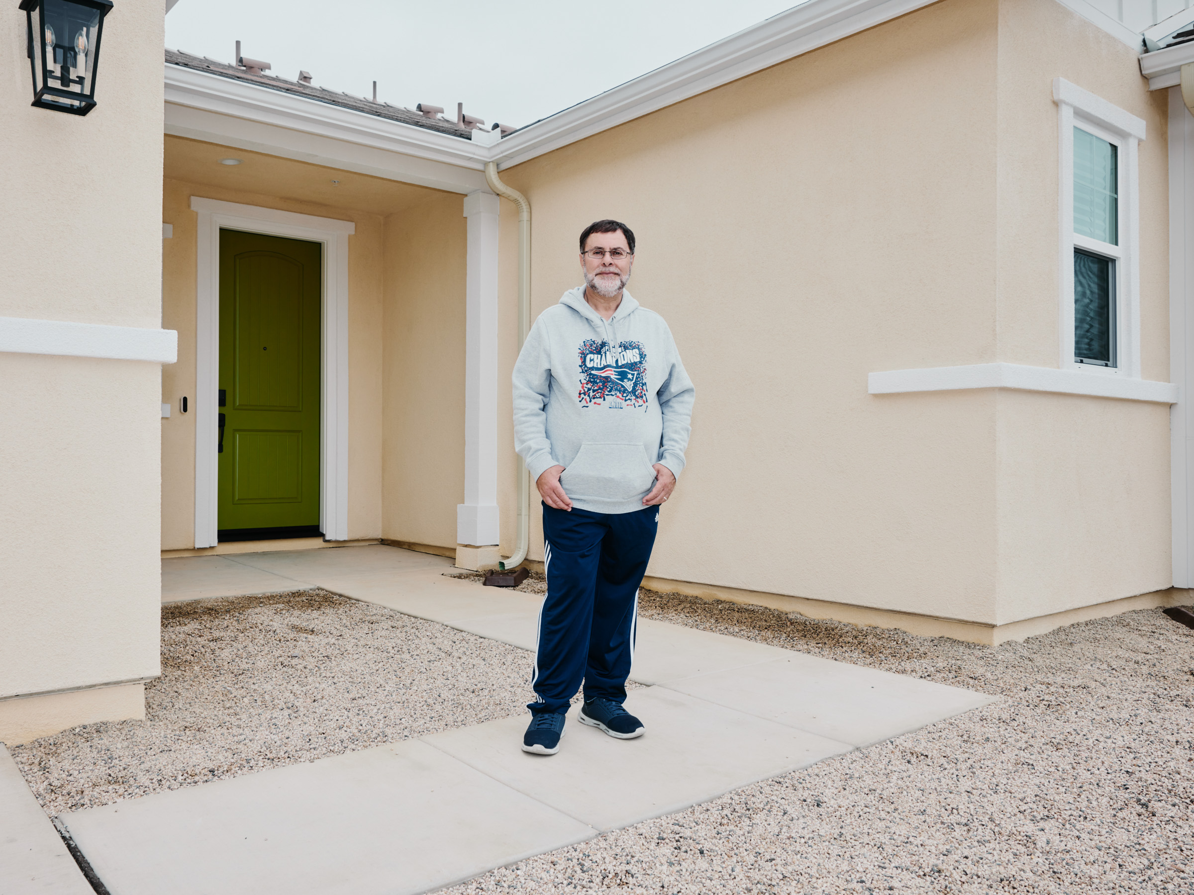 A man stands in front of the door to his home.