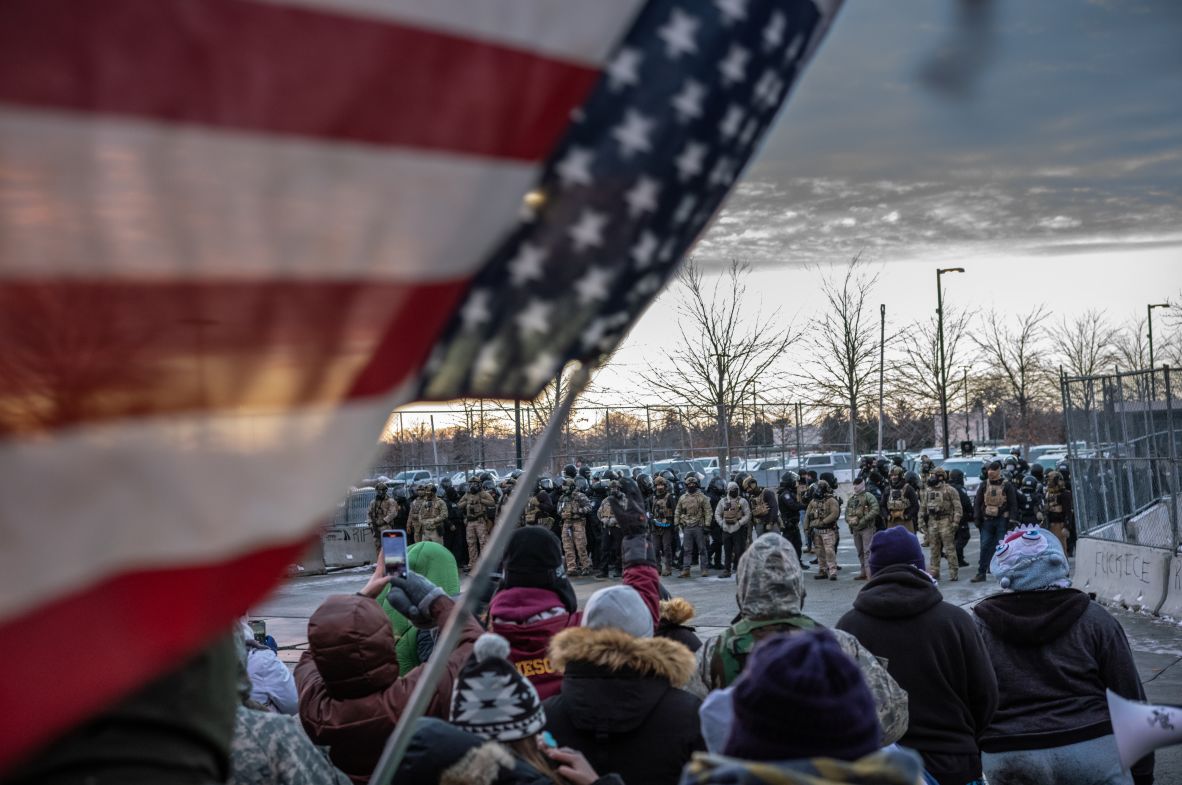 An American flag is waved as protesters face off with agents outside of ICE headquarters in Minneapolis on January 17.