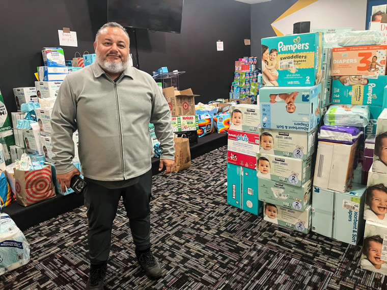 Sergio Amezcua stands next to boxes of diapers and other goods