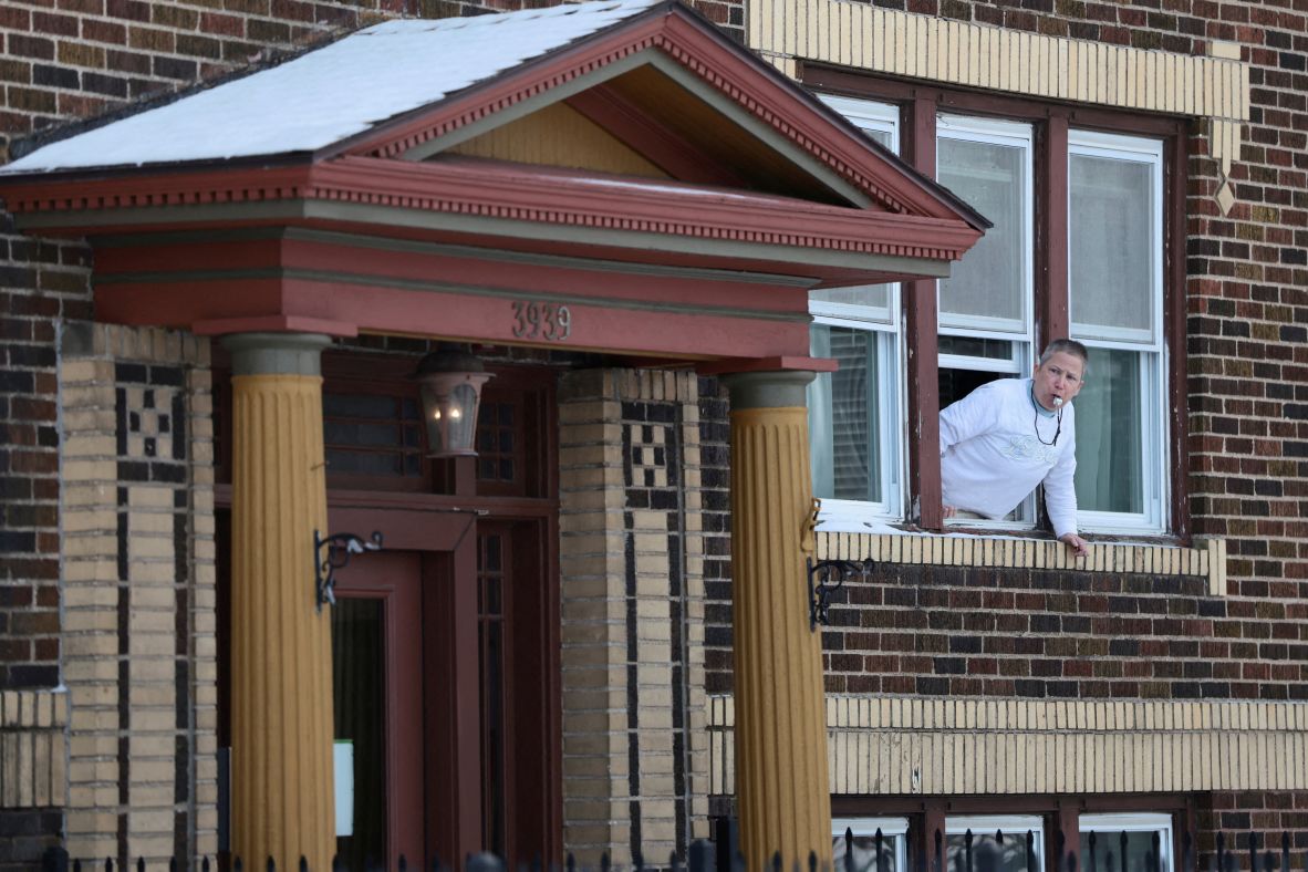 A person whistles from a window as Border Patrol commander Gregory Bovino's convoy drives by in Minneapolis on January 21.