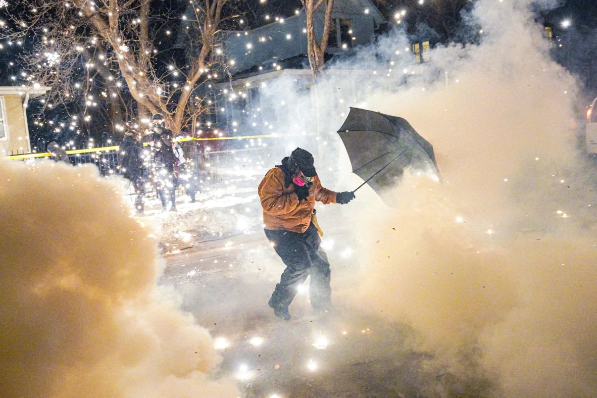 A protester attempts to protect themselves as federal agents fire munitions and pepper balls in Minneapolis on January 14.