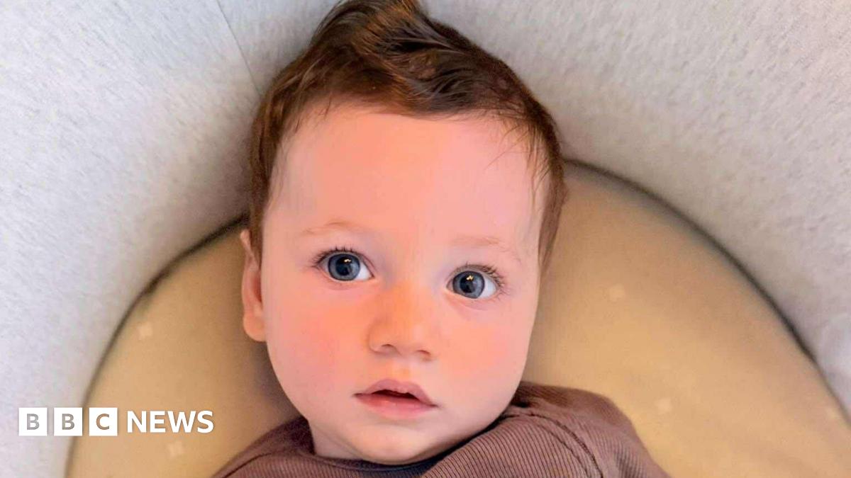 Donald Trump and Keir Starmer sit in a formal drawing room setting  on arm chairs with US and UK  flags behind them. Both have serious expressions and are looking out and not at each other.