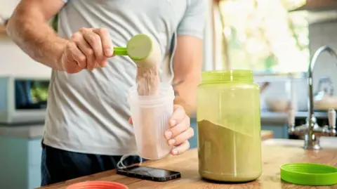 Getty Images Picture of a man putting protein powder into a shaker
