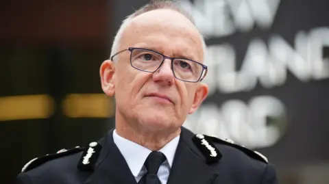 PA Media An image of Sir Mark Rowley standing outside New Scotland Yard in his uniform