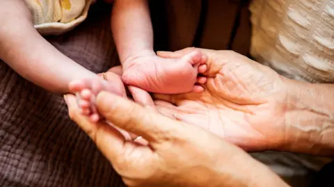 Getty Images A 2-week-old girl and her grandmother in her 60s.
