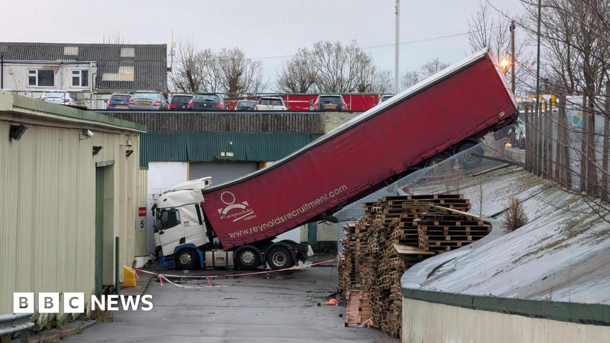 A red lorry that has become stuck after falling into an industrial estate