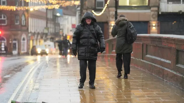 A man walks through the rain in a raincoat