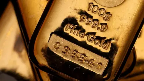 Hiba Kola/Reuters A shining gold bar with "100g, 999.9 fine gold, C 3 5 5 4 1" stamped into it.