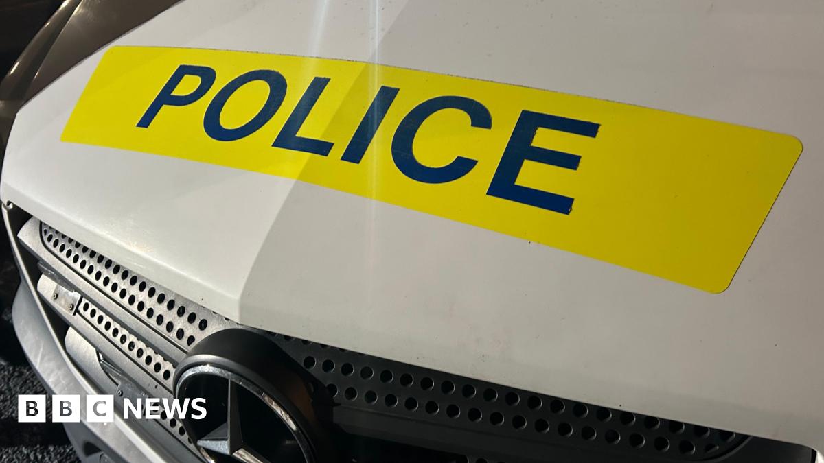 The front of a police vehicle. The vehicle is white and it has the word 'Police' in a yellow box.