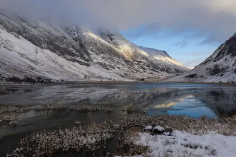 Andrew Briggs Snowy mountains and a frozen loch on a winter's day