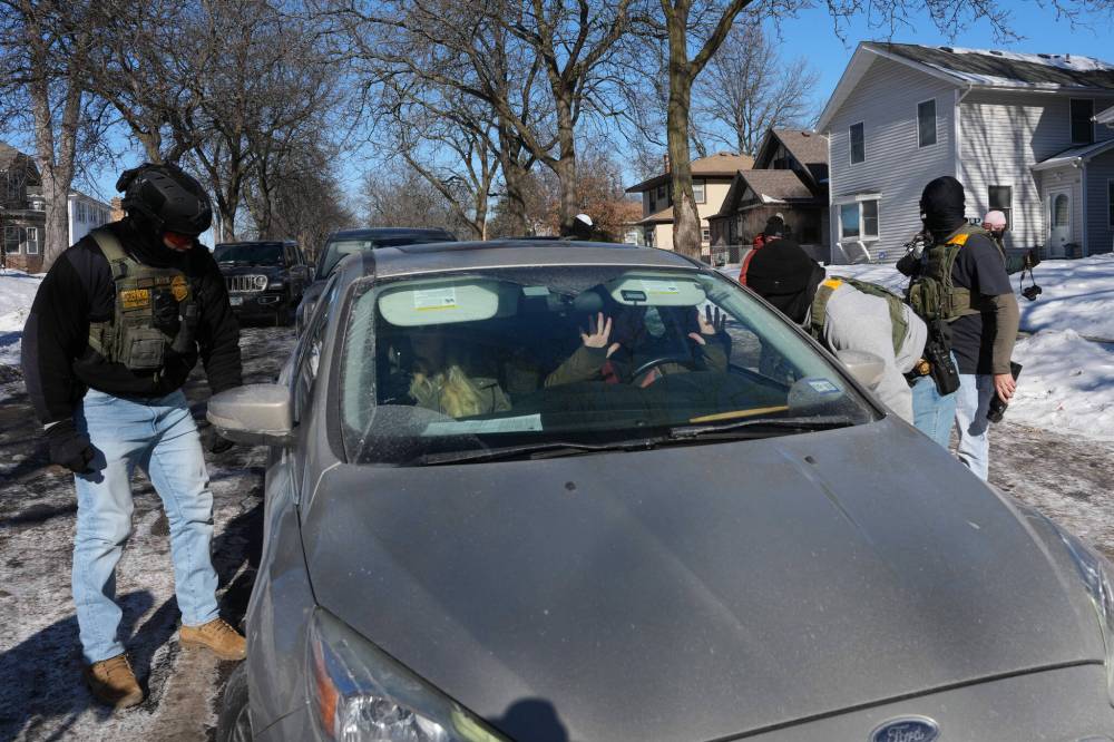 ADAM GRAY / THE ASSOCIATED PRESS
Federal agents approach a vehicle in Minneapolis Thursday.