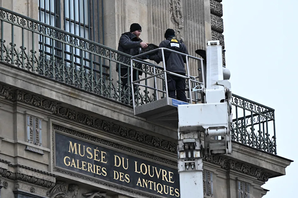 Workers install metal security bars over the window where thieves broke into the Louvre museum. / Credit: Emma Da Silva / AP