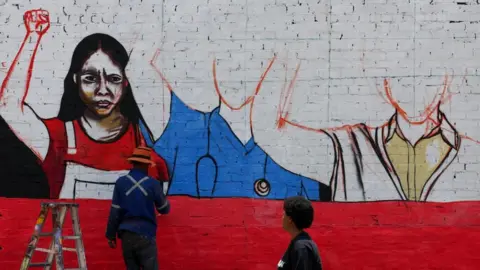 Reuters A person works on a mural with a message against gender-based violence in Johannesburg, South Africa, on 21 November 2025