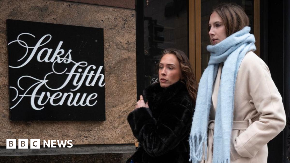 Two people wearing winter clothing leave a Saks Fifth Avenue store.