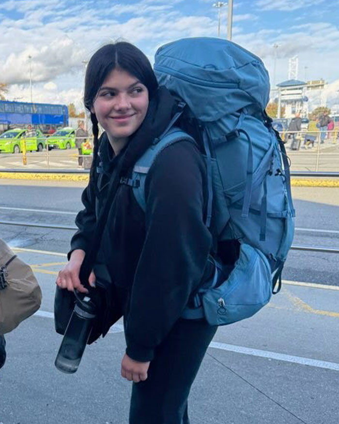 Teen girl with large backpack at transit stop, related to autopsy results uncovering clues in Canadian teen dingo case.