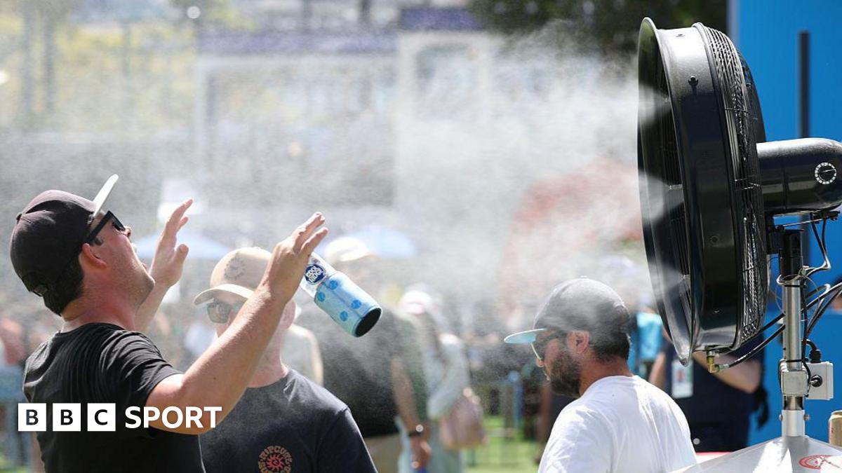 A man stands in front of a water mister in Melbourne Park