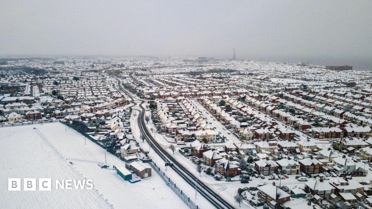 A wide shot of Blackpool from above, the fields and houses are covered in snow. Blackpool tower can be seen in the distance
