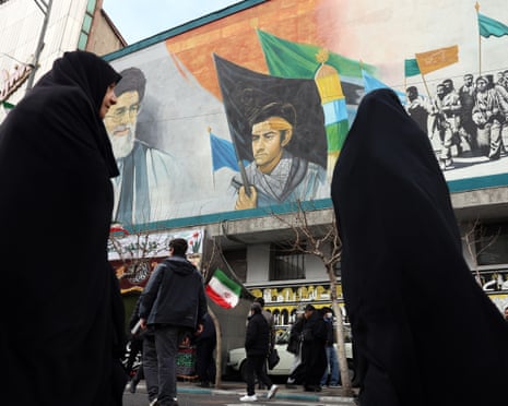 Iranian women wearing chadors walk near a mural depicting Iranian supreme leader Ayatollah Ali Khamenei in Tehran
