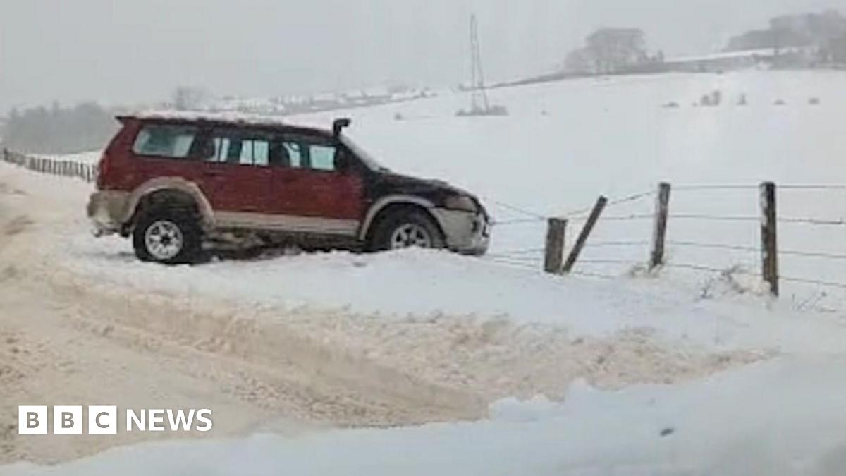 A red 4x4 car skidded off a snowy road into a fence by a snowy field
