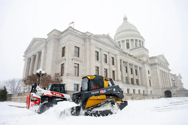 Two diggers move snow from outside the Arkansas State Capitol building