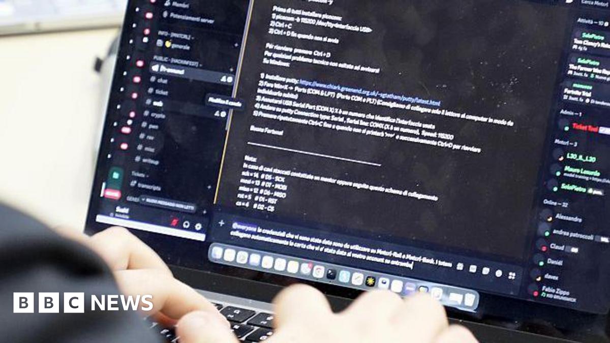 A computer keyboard with code on it and the operator's hands.