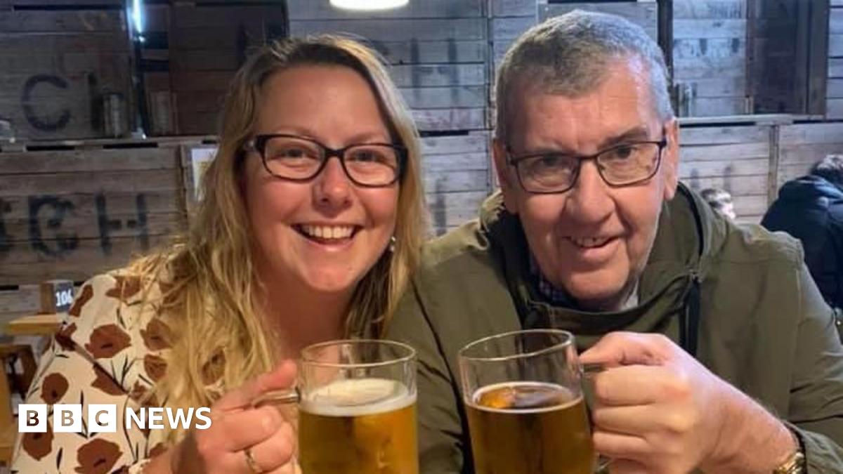 Maureen (left) and Tony Dynes in a pub, smiling at the camera and holding up pints of beer. Maureen has long blonde hair and is wearing a patterned cream top with red flowers. Tony has short grey hair and is wearing a green jacket. Both are wearing glasses.