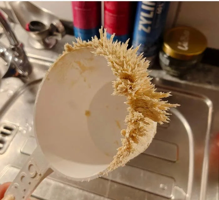 A kitchen sink scene with a spoon encrusted with hardened powder, likely from previous mixing or baking