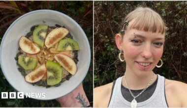 A photo from above of a table with bowls of chickpeas, mashed avocado, nuts, seeds and salads. In the middle of the table, a pair of hands are spreading avocado on slice brown bread