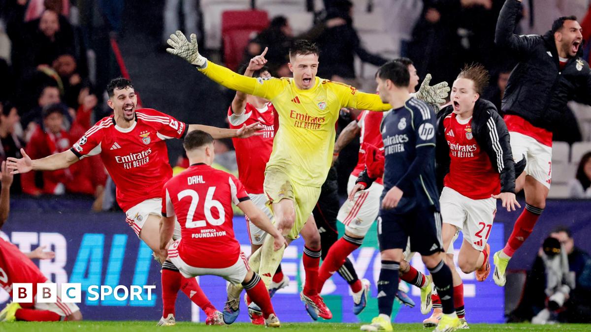 Goalkeeper Anatoliy Trubin celebrates scoring for Benfica against Real Madrid. In a yellow kit he runs among joyous team-mates who are wearing red and white kit