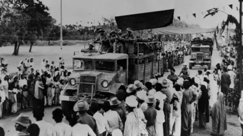 Getty Images November 1962: Crowds lining the streets watch as Indian troops drive by in trucks in the Ladakh region of northern India during border clashes between India and China. (Photo by Radloff/Three Lions/Getty Images)