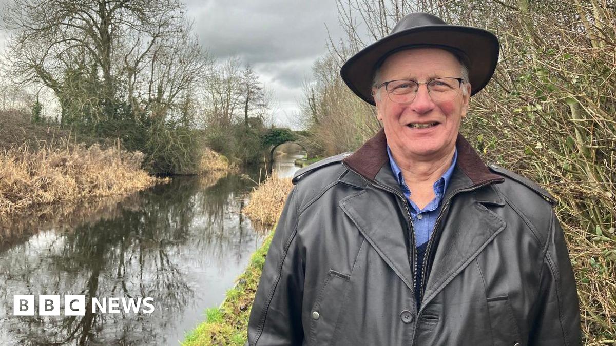 Prime Minister Mark Carney, wearing a black suit jacket, and a white button-up shirt leans his chin on his hands. He has short grey and black hair and is looking away from the camera.