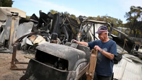 Reuters Harcourt CFA first lieutenant Tyrone Rice inspects damage to his property, amid bushfires in Harcourt, Victoria, Australia, January 10, 2026.