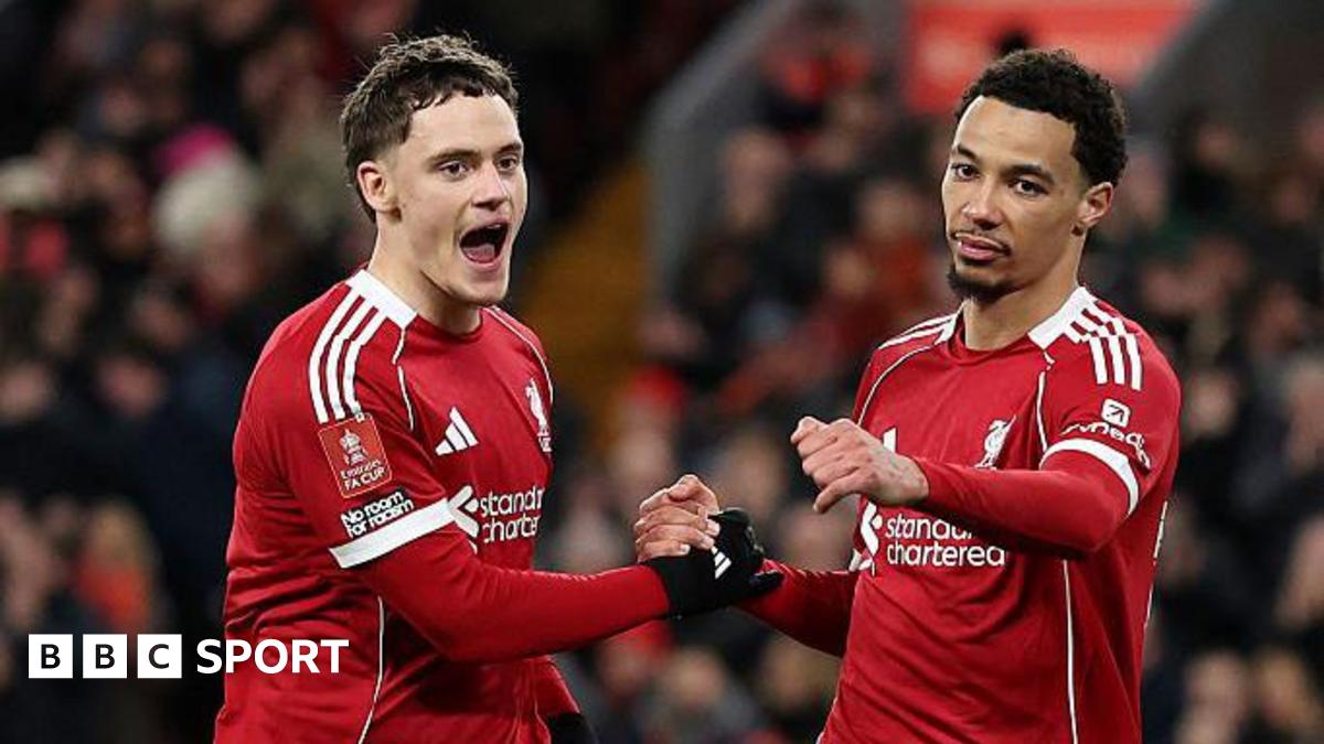 Adam Phillips of Barnsley scores past Giorgi Mamardashvili of Liverpool as teammate Dominik Szoboszlai reacts after making a defensive error.