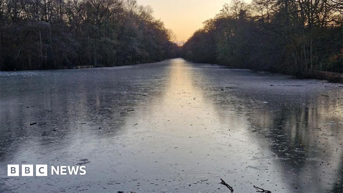 Lincolnshire Police picture of the frozen lake at Hartsholme Country Park. It show a stretch of water with trees along both banks.