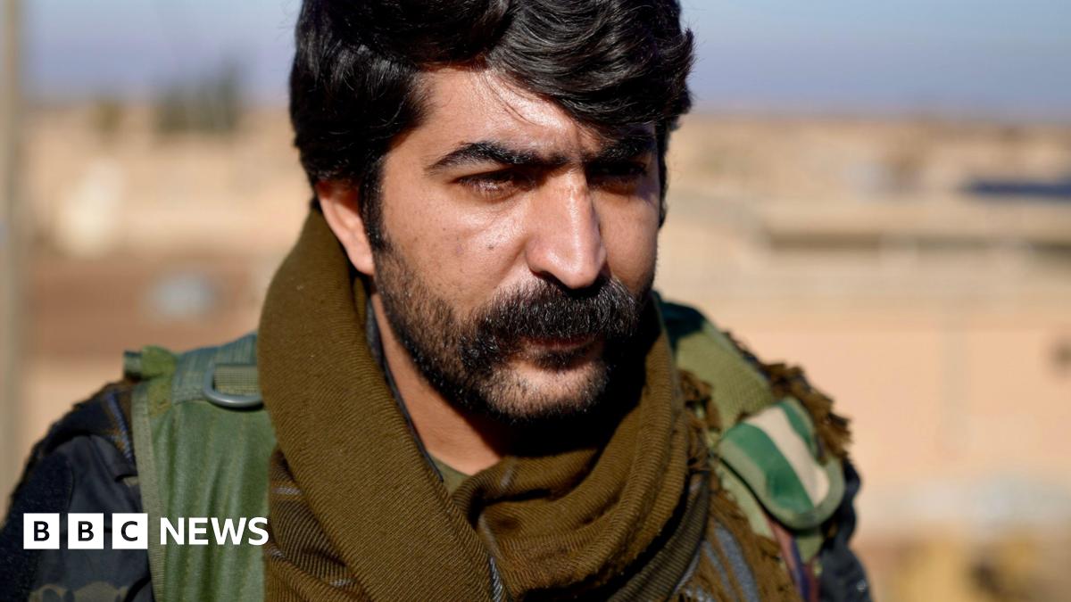 Kurdish soldiers stand on a wall with their weapons in hand